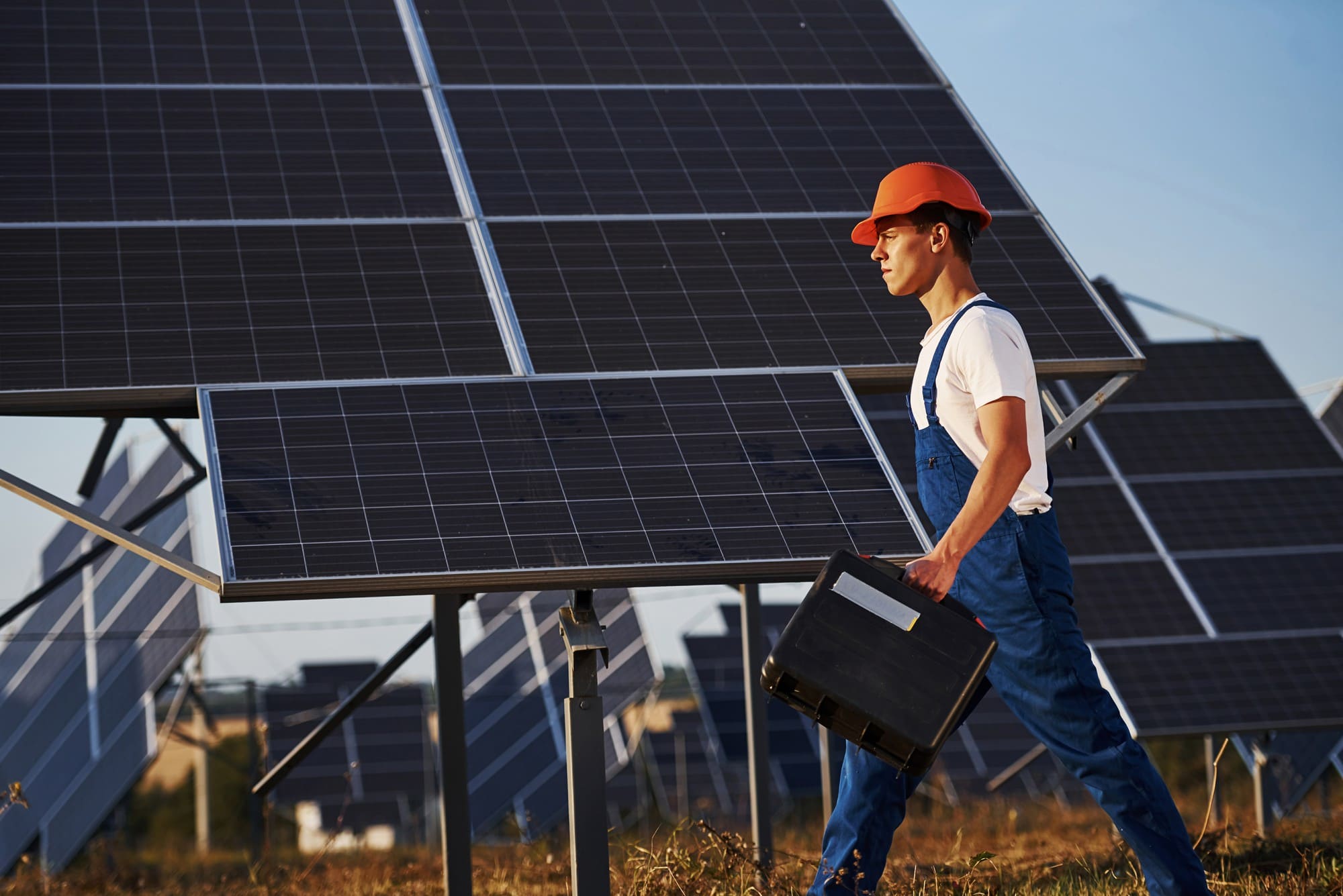 Solar maintenance technician inspecting utility-scale solar panels for renewable energy system performance and efficiency